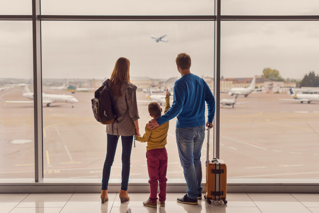 Família no aeroporto olhando os aviões no aguardo de seu voo da GOL no qual acumulou milhas com relação as novas regras Smiles.